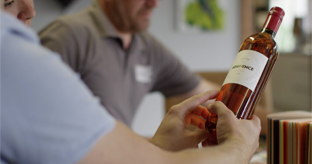 Male hands hold a bottle of wine with pink liquid inside