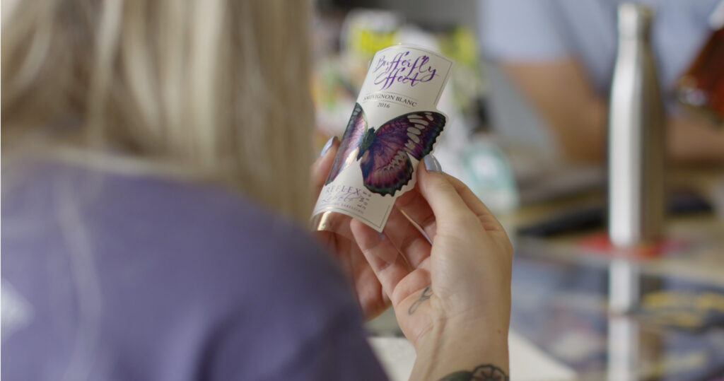 Female hand holding a label with a purple butterfly on it