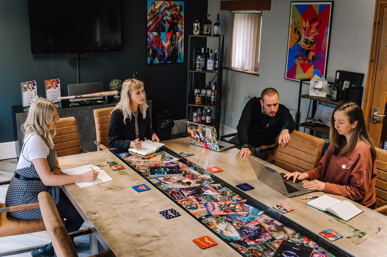 Four people sat around a large conference table, one looking at a laptop