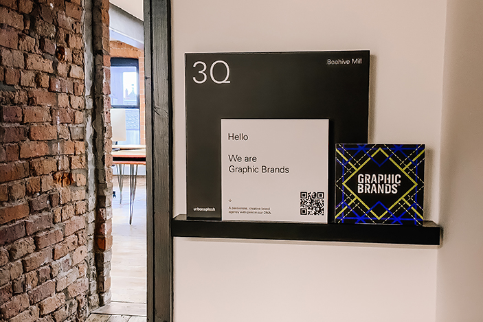 Two small square signs open a black shelf outside an open door leading into an office