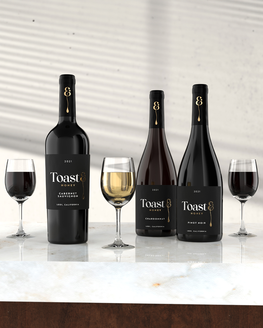 Toast and Honey Wines set up on top of a marble background with a glass of wine alongside each bottle